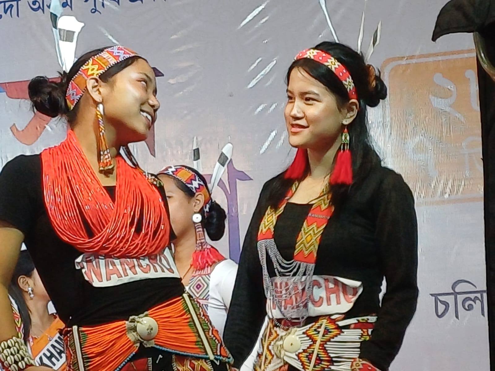 Two students in Wancho dress, smiling at each other